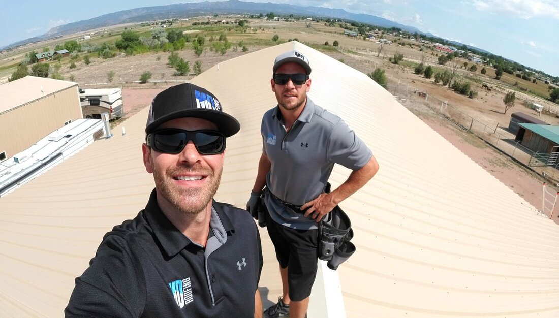 Two MD Roofing specialists on a roof, smiling